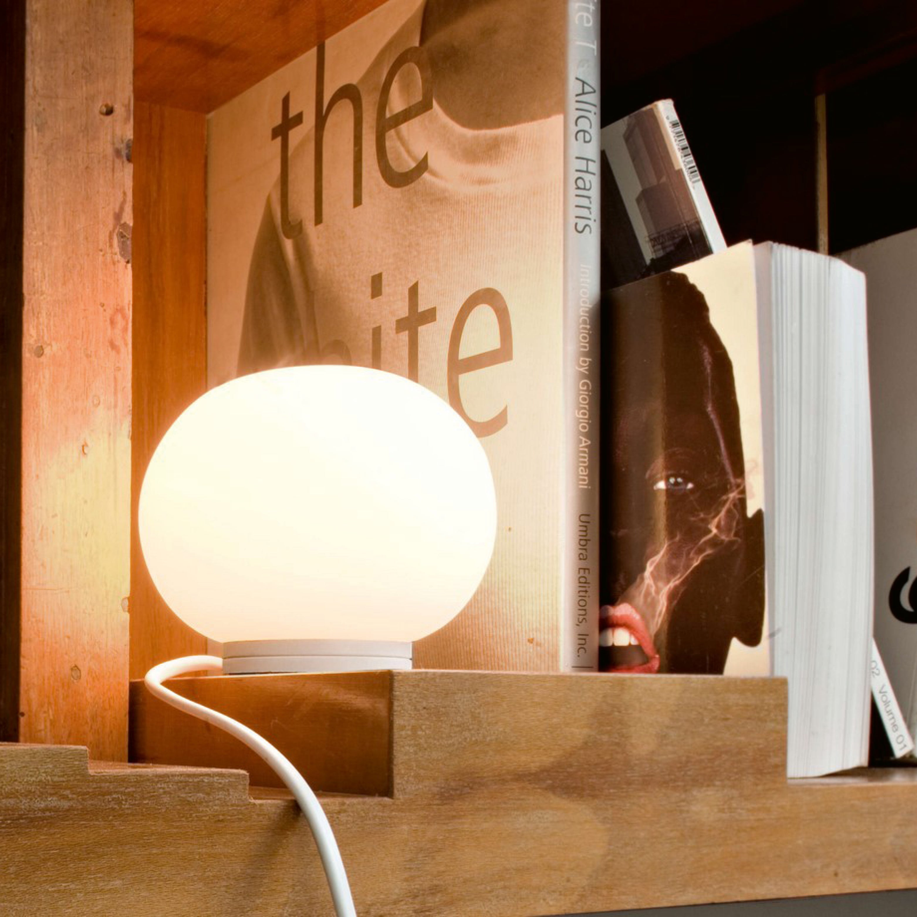 Kleine runde Opalglaslampe die an ist im Bücherregal – stimmungsvolle Dekorationsleuchten.