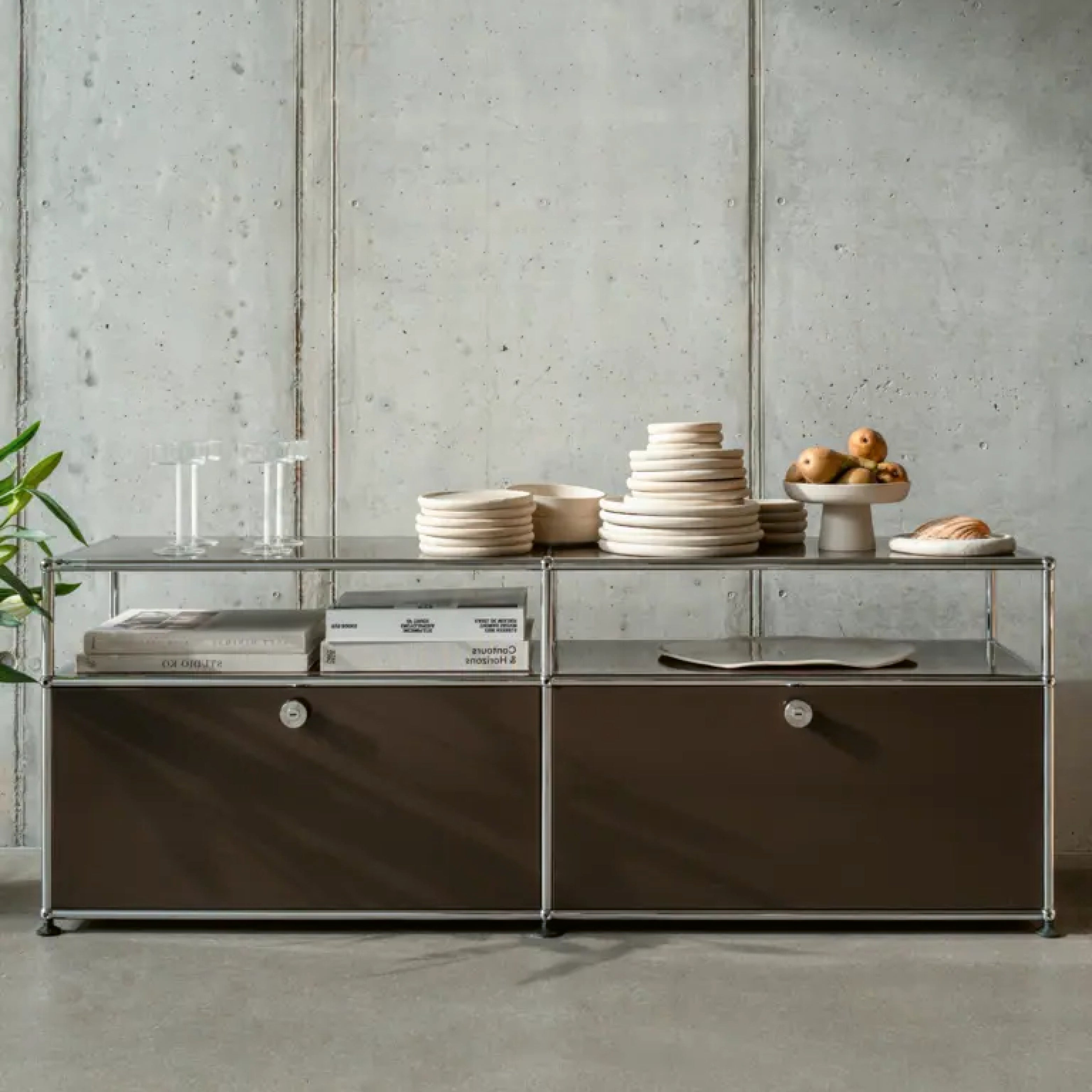 Modulares Sideboard aus Stahlrohr mit braunen Fronten und offenem Regalteil, gedeckt mit Geschirr und Gläsern