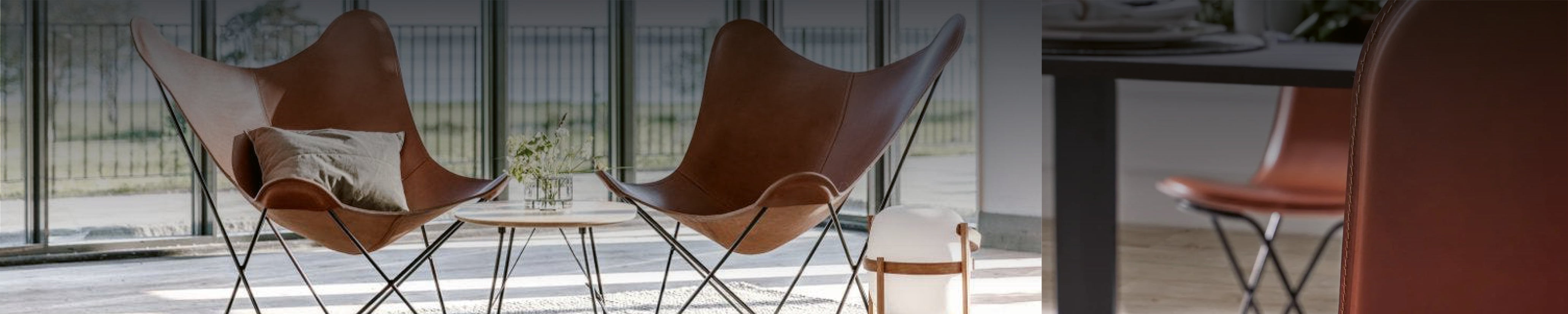 Zwei Cuero Butterfly Chairs in Cognac-Leder – Designklassiker mit schlankem Metallgestell vor großen Fensterfronten