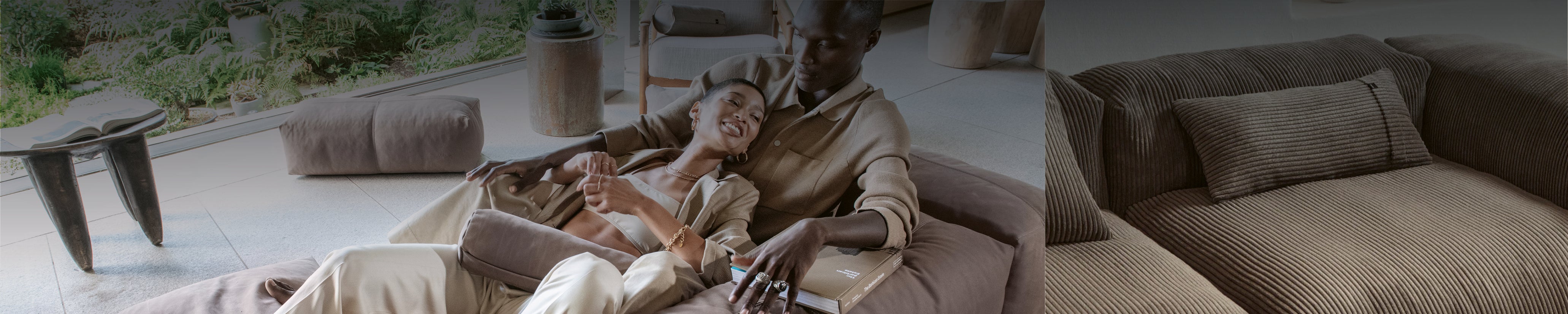 Zwei Personen entspannen auf einem modularen Vetsak Sofa mit Cordstoff in einem modernen Wohnzimmer mit Gartenblick