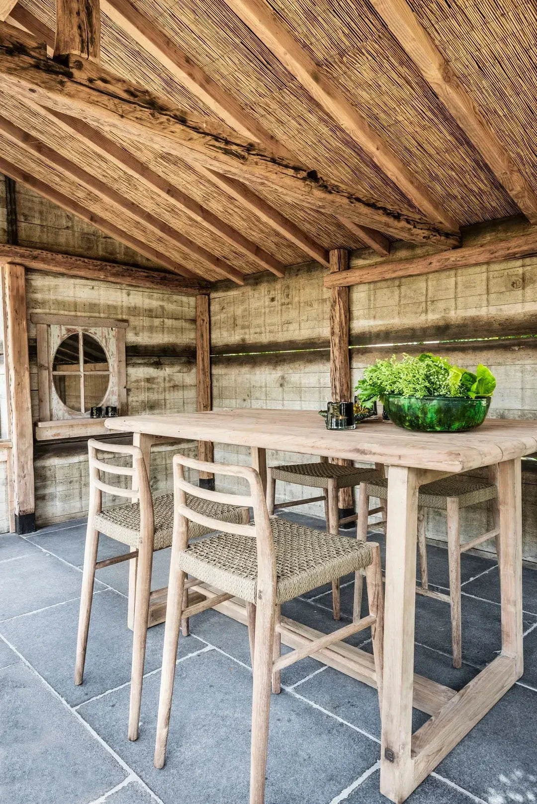 Bartisch DENNIS aus Teakholz, stilvoll integriert in einen modernen Outdoor-Barbereich mit Barhockern – ideal für geselliges Beisammensein im Garten oder auf der Terrasse