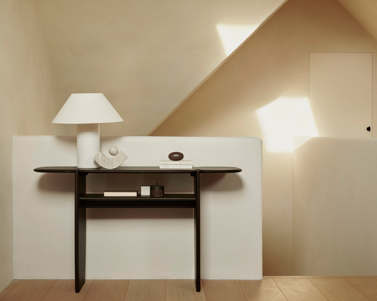 Ethnicraft PI console table, 130 x 75 cm, made of dark brown mahogany, with decorative objects in a bright entryway.