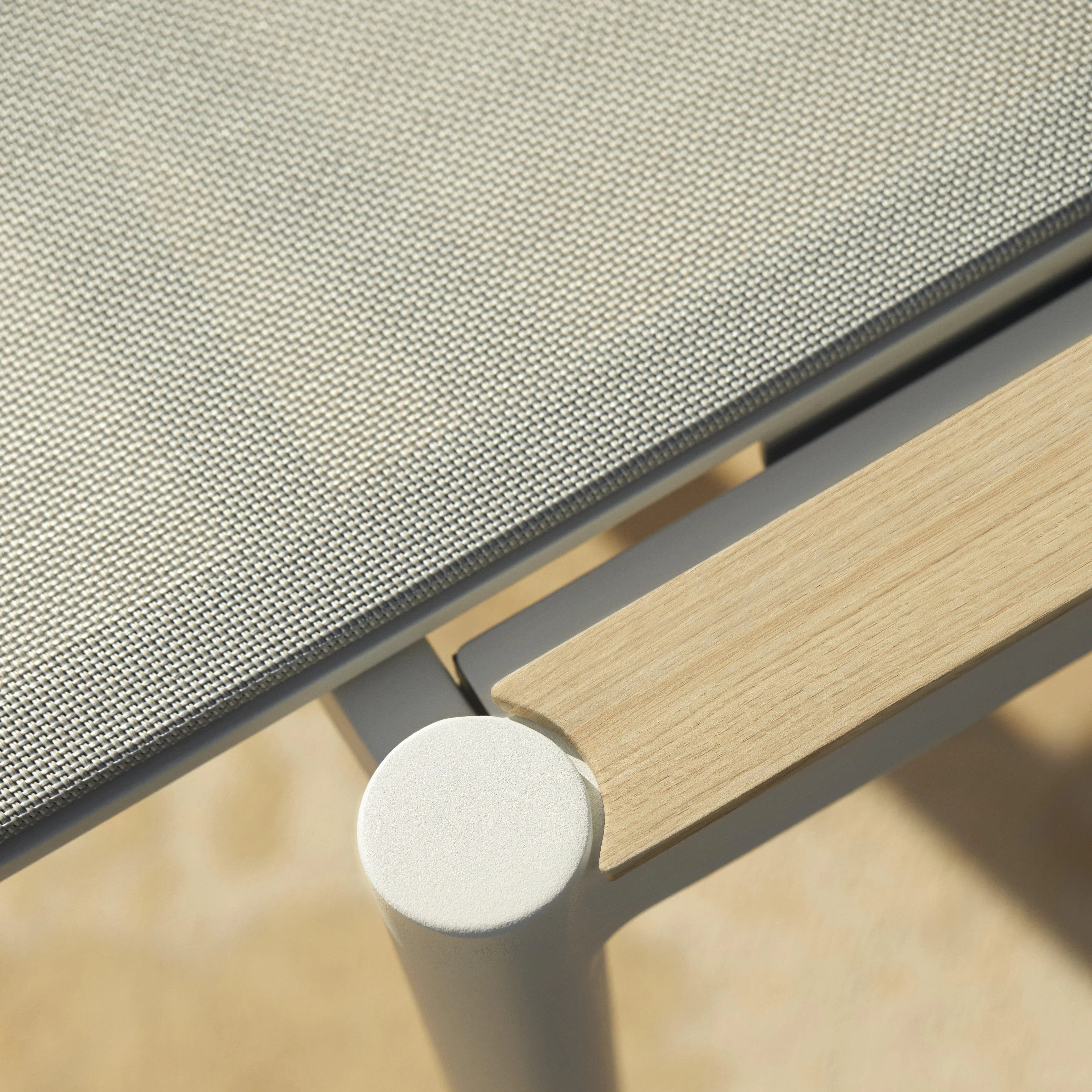 Detailansicht der STYLETTO Sonnenliege – präziser Übergang von der massiven Teak-Armlehne zur gepolsterten Liegefläche in Weiß