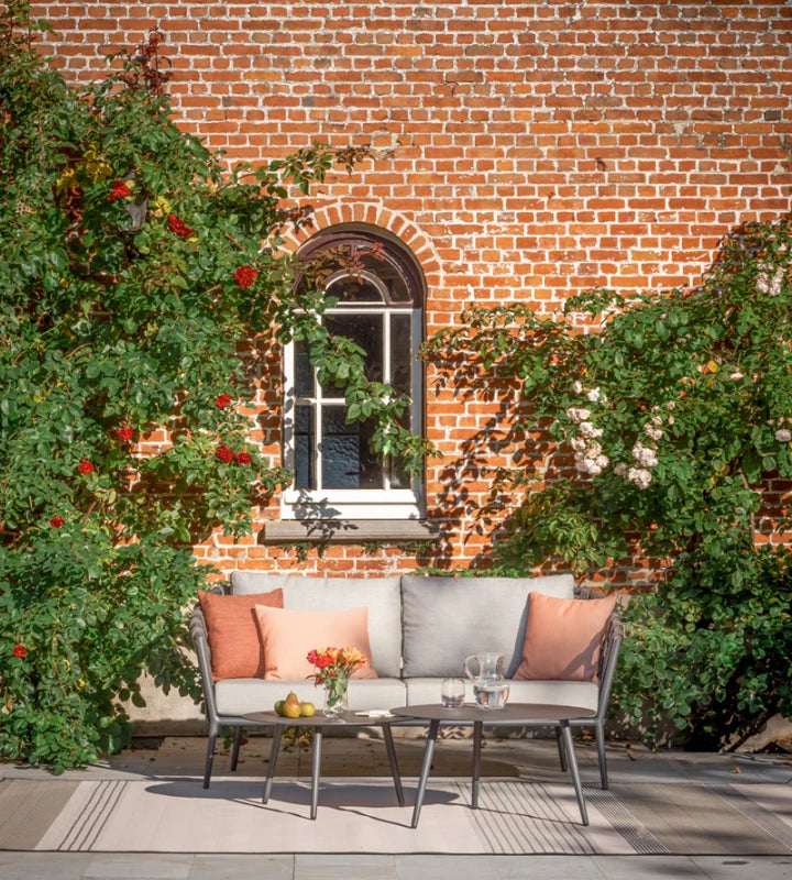 Table basse LEO de Vincent Sheppard, couleur « Lava », devant un canapé de jardin sur la terrasse
