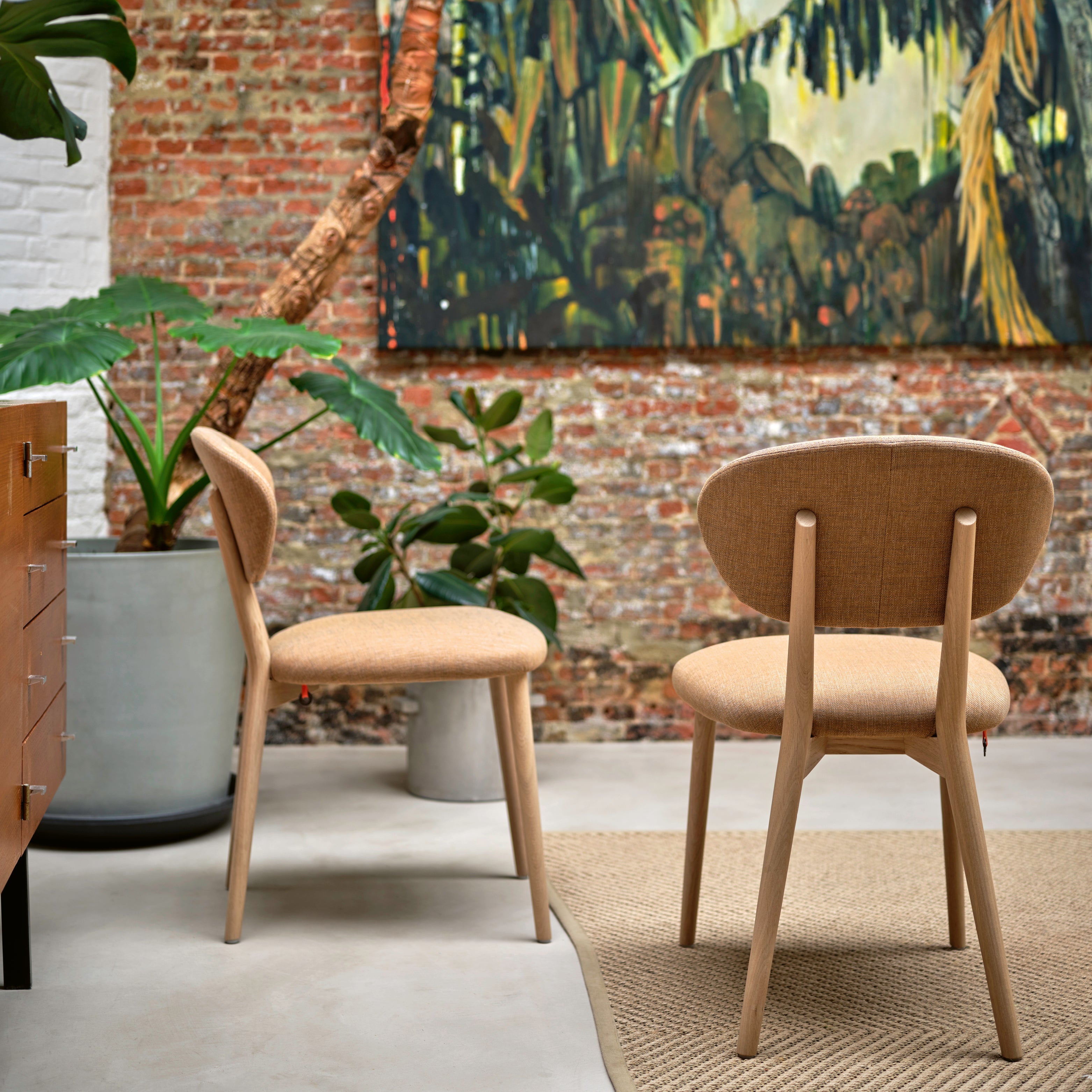 Heller, orangefarbener Stoffstuhl in einer modernen Loft-Wohnung, kombiniert mit schlichten Möbeln und viel Tageslicht – sitzmöbelstarker Akzent für innen.