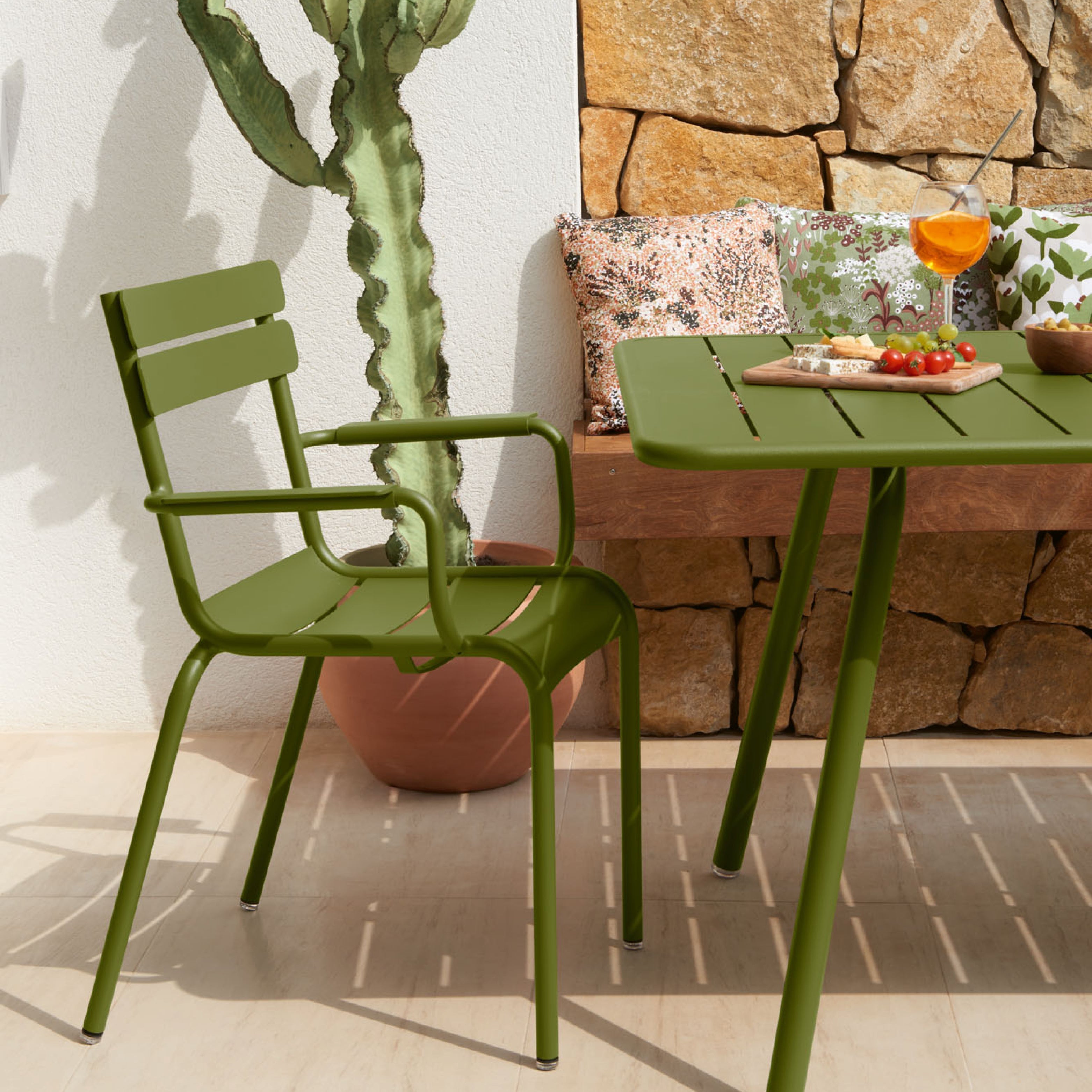 Grüner Outdoor-Stuhl und Tisch aus Metall von Fermob, Modell Luxembourg, auf Terrasse neben Steinwand