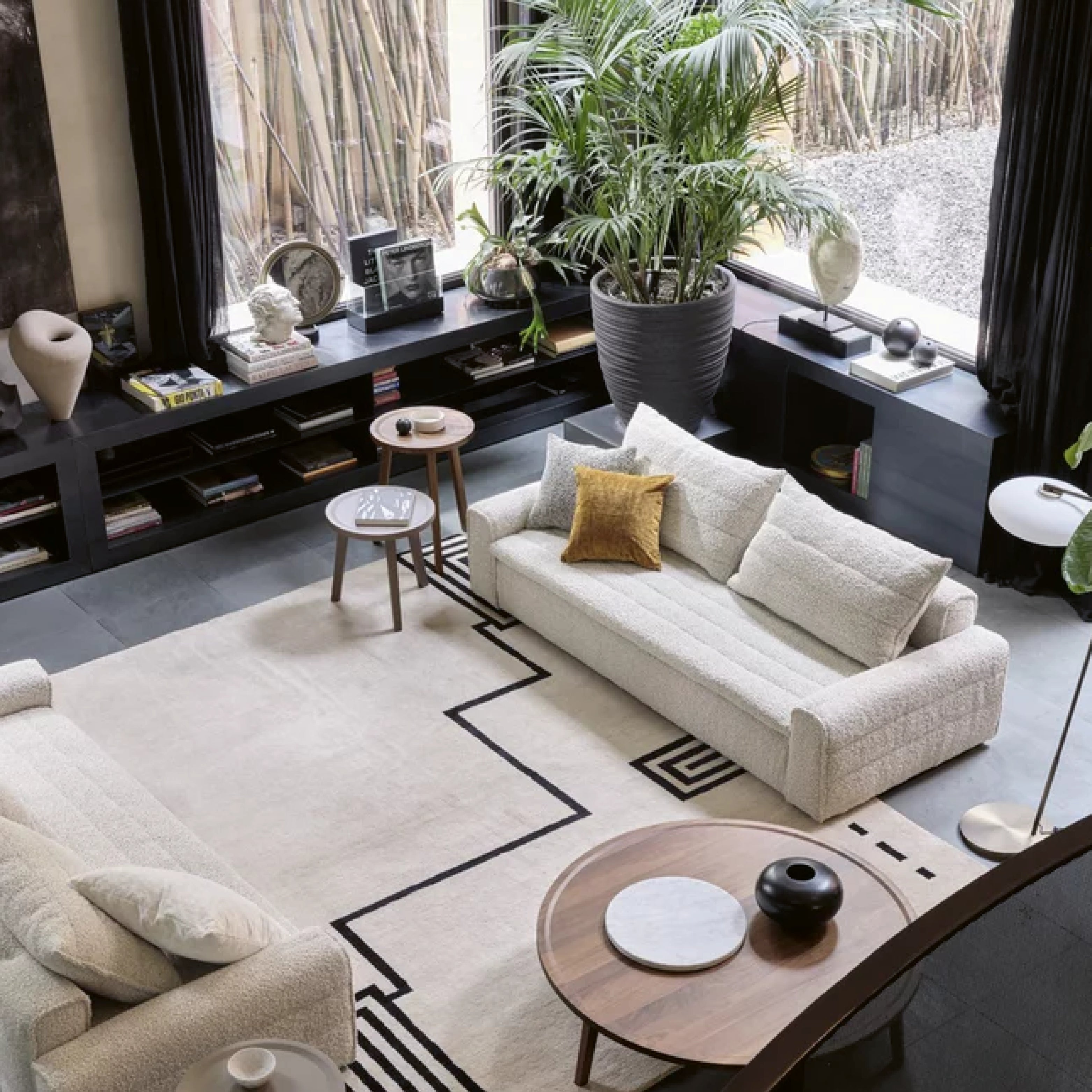 Wohnzimmer mit Gervasoni Sofa in hellem Stoff, Design-Teppich und runden Beistelltischen in Holzoptik