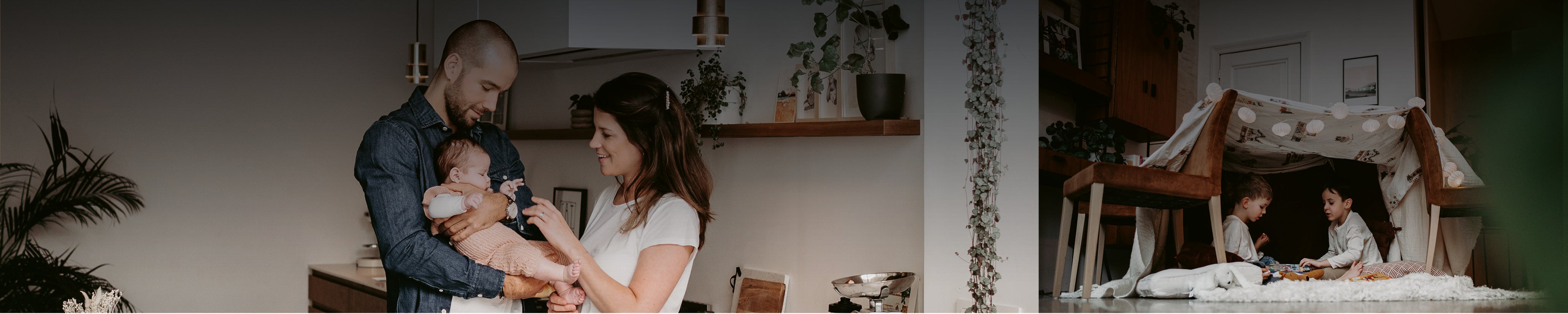 Weitwinkelansicht mit Eltern und Baby in der Küche links und zwei Kindern in einem selbstgebauten Decken-Zelt rechts – lebendige Family Homestorys Momentaufnahme im Zuhause.