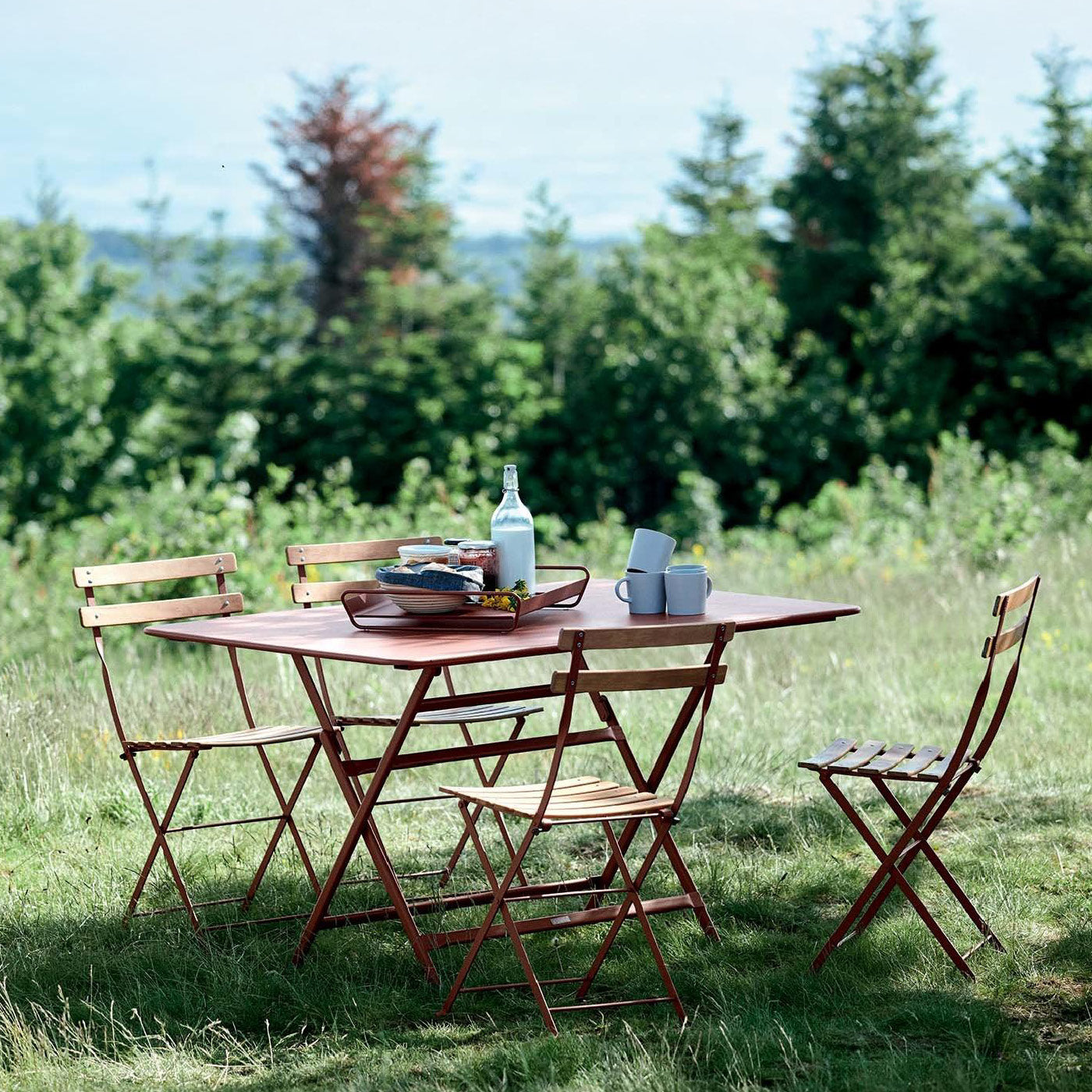 Fermob-Klapptisch und Stühle in grüner Landschaft.