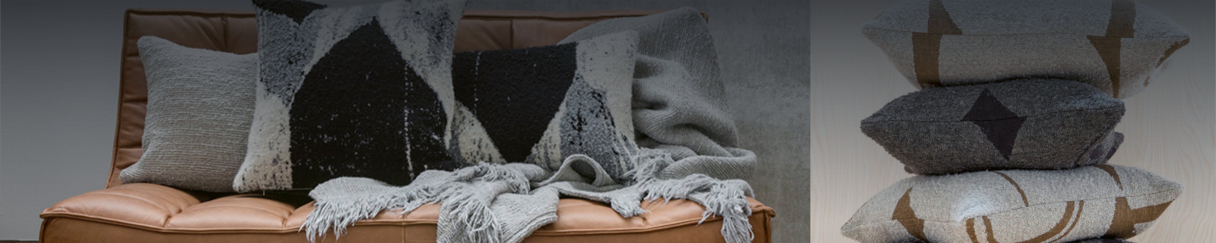 Detailaufnahme weicher Ethnicraft-Plaids in Naturfarben auf Sofa – gewebte Muster, dezente Farbkontraste und gemütliche Atmosphäre in modernem Raum.