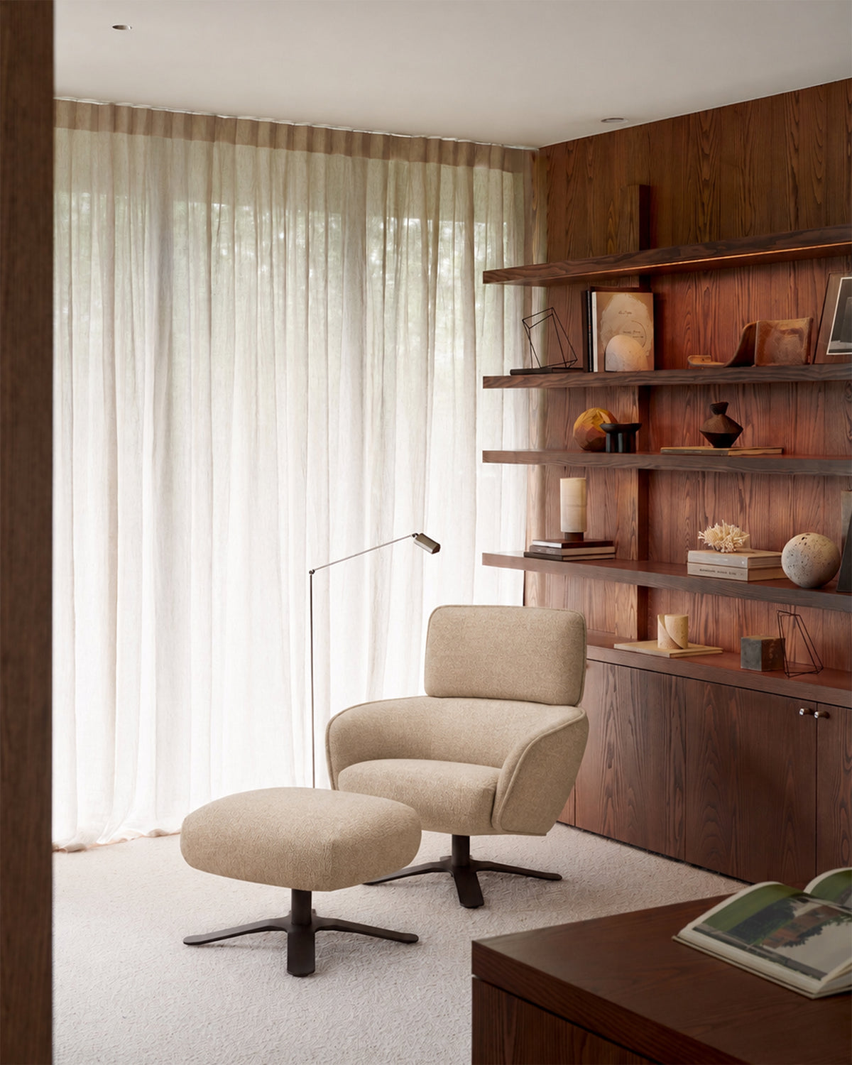 Ethnicraft MERGE footstool with soft padding in front of a lounge chair in a reading nook.