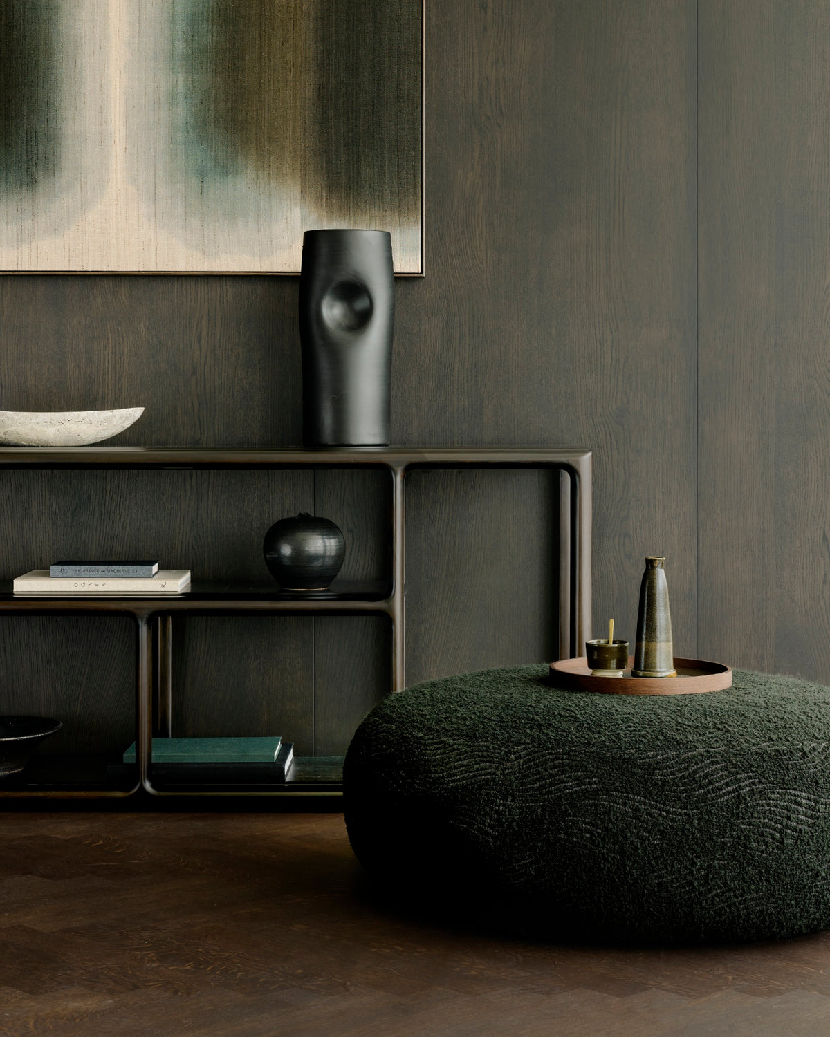 Ethnicraft ORB ottoman in Forest, used as an upholstered footstool in front of a lounge chair in a cozy living room.
